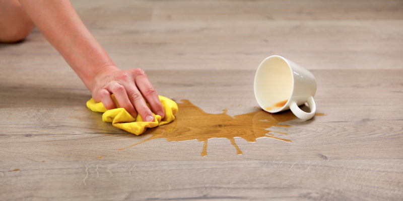 coffee getting wiped up from spilled on a hardwood floor