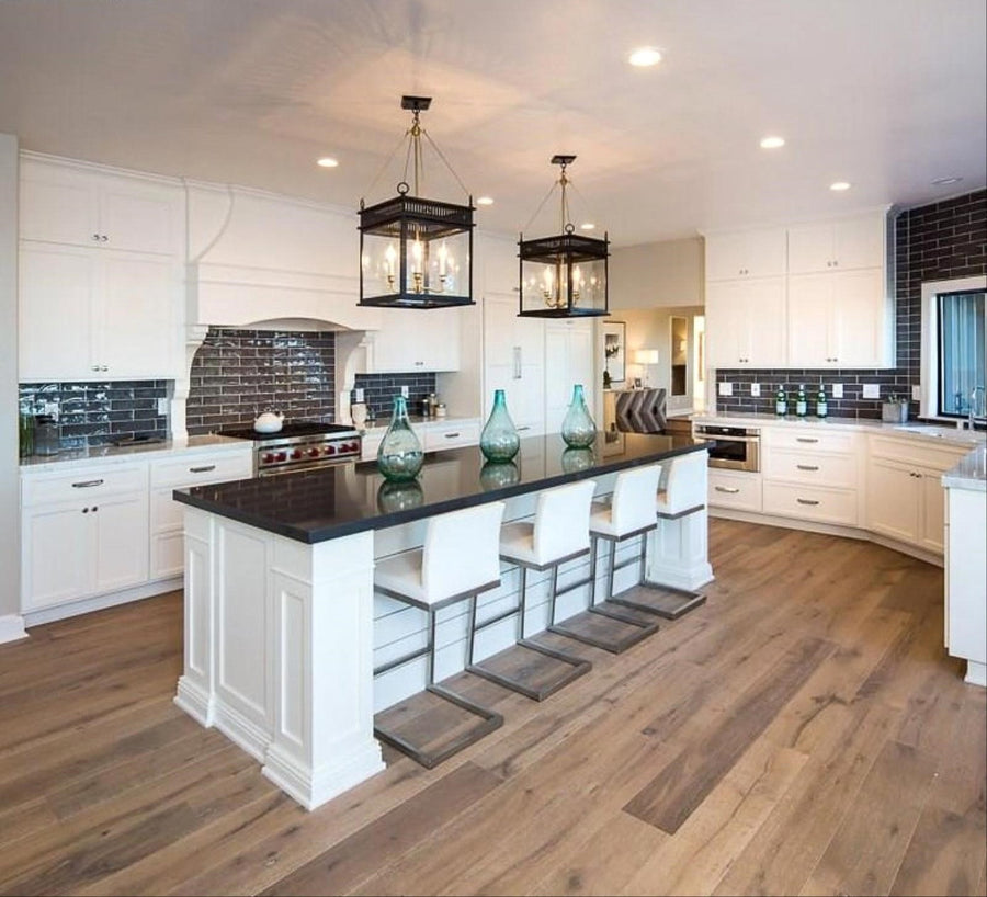 A kitchen with white cabinets and a dark stone island, floored in wide-plank Arizona engineered hardwood in Tempe Taupe