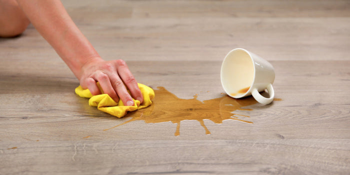 coffee getting wiped up from spilled on a hardwood floor