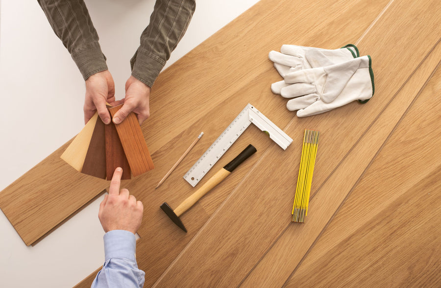 Hands holding a fan of wood-look flooring samples while choosing between them