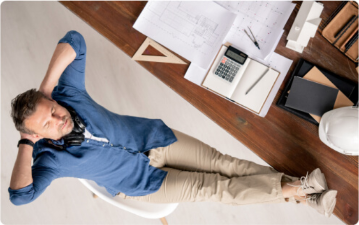 A man is resting on his office chair at his desk.